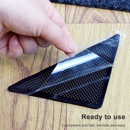 Non-Slip Stickers for Safer Bathroom Floors at Home - hand applying clear non-slip sticker to bathroom rug corner on wet wood floor for safety