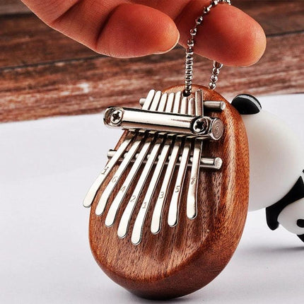 A Compact Thumb Piano for Daily Musical Expression - pocket-sized wooden kalimba keychain with metal tines being held