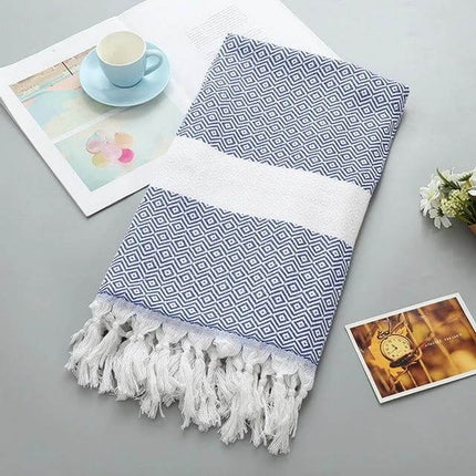 Striped Cotton Bath Towel With Tassels For Everyday Use folded blue geometric stripe towel with white tassels on table
