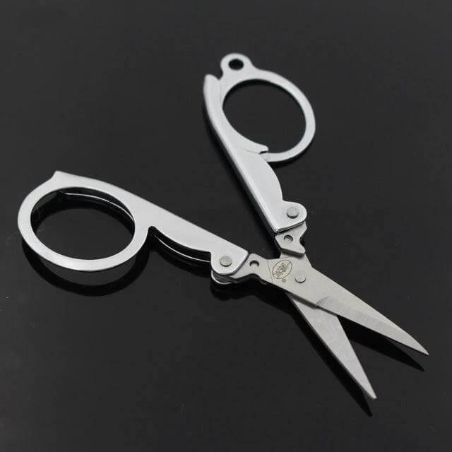 Travel Portable Mini Folding Scissors For Home And On The Go compact stainless steel silver V-blade scissors folded open on black surface