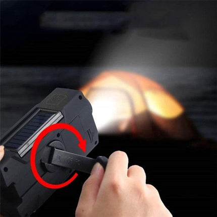 Hand Crank Solar Powered Emergency Radio with Flashlight and Weather Alert being hand-cranked to power the flashlight and charge phone via USB during an outage