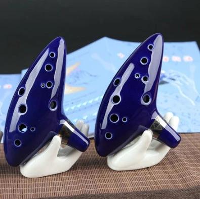 Ocarina for Beginner Musicians to Enjoy Music at Home - blue glazed ceramic ocarina on hand-shaped stands for casual home practice