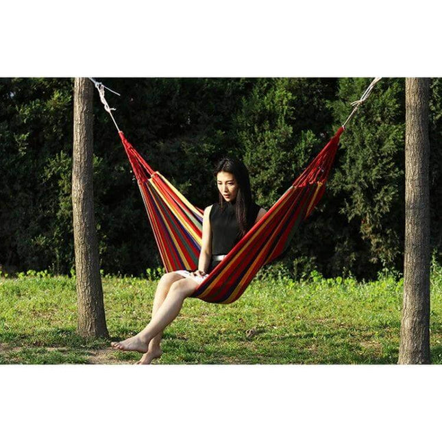 Thick Canvas Hammock For Outdoor Relaxation 260x150 hung between trees with person reading in backyard