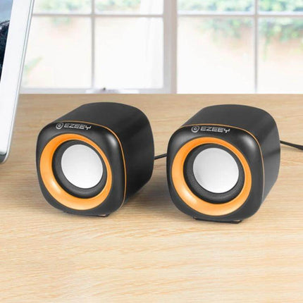 YEEZE Compact USB Desktop Speaker For Laptops And Meetings on a desk near laptop, compact black-orange USB speakers for meetings