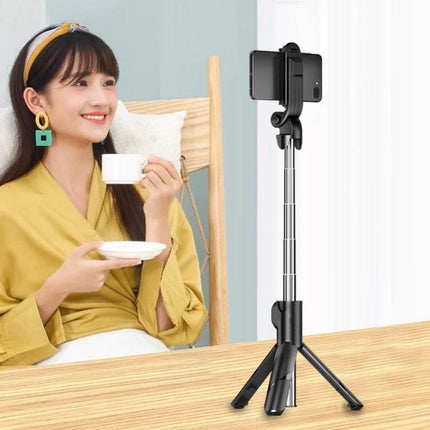 Woman using Compact Selfie Stick for Daily Travel and Event Photos on table with phone mounted, compact tripod extended for steady selfies