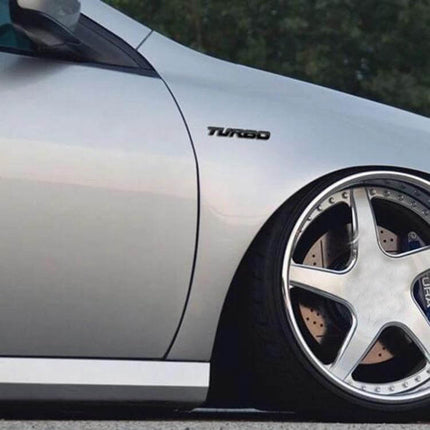 Set of 8 Metal Turbo Car Stickers for Sports Vehicle Decoration - close-up of silver sports car side with 3D TURBO metal badge above alloy wheel