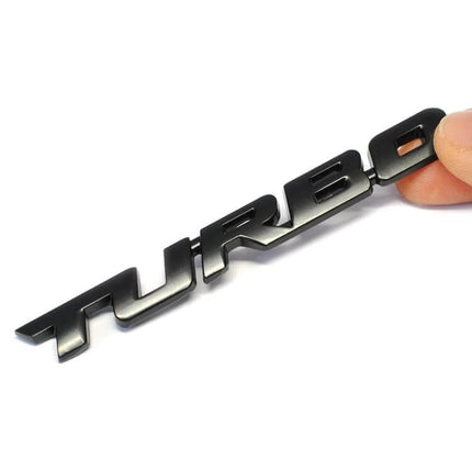 Set of 8 Metal Turbo Car Stickers for Sports Vehicle Decoration — close-up black 3D TURBO zinc alloy badge held by hand, weatherproof car decal