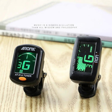 Aroma Clip-On Tuner for Everyday Instrument Tuning at Home - two black clip-on tuners with green LCD displays on a wooden table