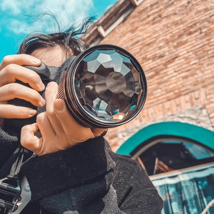 Photographer holding lens with 77mm Kaleidoscope Prism Glass Filter for Creative Photography creating refracted patterns