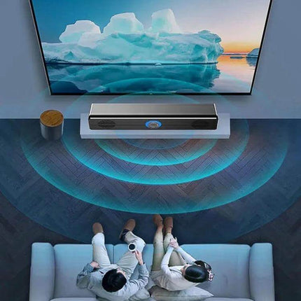 LeerFel Computer Speaker Bluetooth USB Powered Desktop placed under TV on a desk, angled cabinet projecting sound to sofa viewers