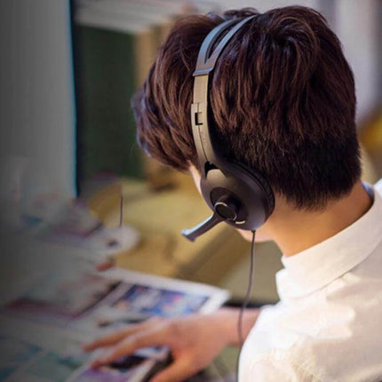 Edifier USB Gaming Headset For Desktop Gaming And Video Calls worn by user at desk with adjustable mic and inline controls, wired USB/3.5mm