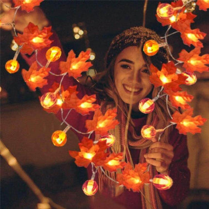 Maple Pumpkin Lantern String Lights For Halloween Decor draped around smiling woman, warm maple leaf and pumpkin LED lantern glow for fall mantel or table display