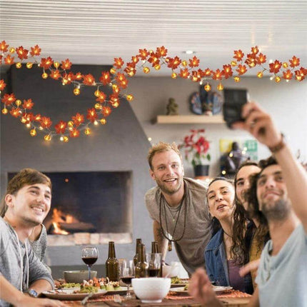 Maple Pumpkin Lantern String Lights For Halloween Decor draped above a cozy friends' dinner with warm lantern-style LED glow