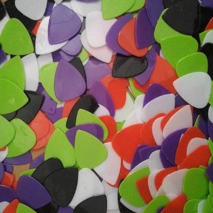 Colorful stack of plastic guitar picks for everyday music practice at home, assorted green purple red white and black picks