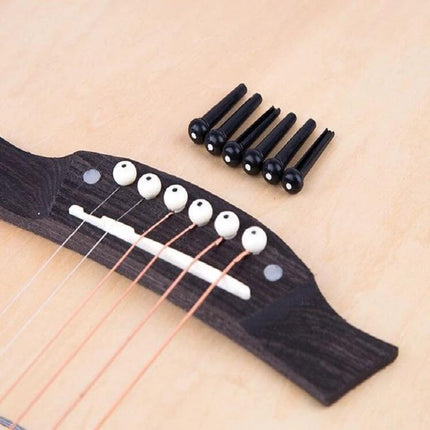 Plastic Conical Pins for Everyday Guitar String Maintenance shown next to acoustic bridge with strings and white bridge pins
