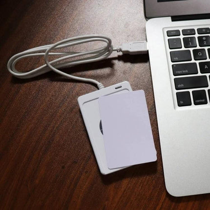 Portable USB-Powered Contactless NFC Card Reader for RFID Access connected to laptop via USB with white RFID card on wooden desk