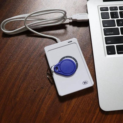 Portable USB-Powered Contactless NFC Card Reader for RFID Access connected to laptop with blue RFID key fob on wooden desk