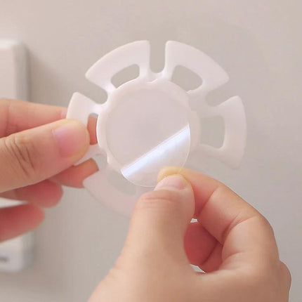 6 Pack Cable Organizer Winder Traceless Paste Hook For Power And Data Cables - white PP cable winder with adhesive backing being applied to wall, compact 6.5x3.5x3cm