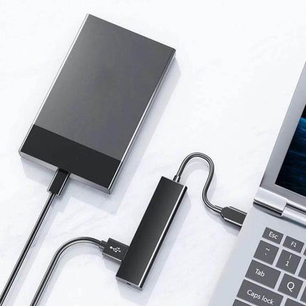 Compact Four-Port USB Hub for Connecting Devices Daily — slim black four-port USB 2.0 hub connected to laptop and external drive, tidy home office setup