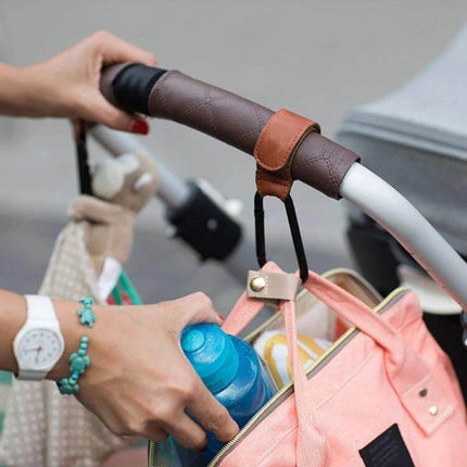 Two Pack Baby Stroller Carabiner Hooks, Brown and Black securely hanging a diaper bag and bottle from a stroller handle for convenient outings
