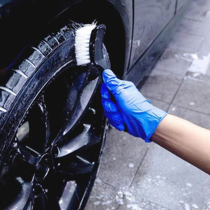 Effective Carpet and Upholstery Cleaning Brush with Curved Design being used to clean a car tire and wheel with soapy water