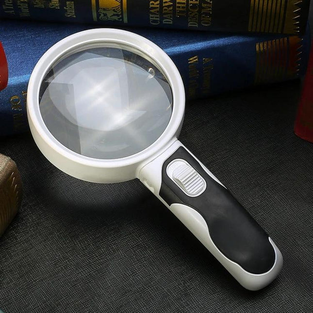 Hand-Held LED Magnifier for Reading and Repair, 10x Magnification - white and black magnifier with LED switch on dark background