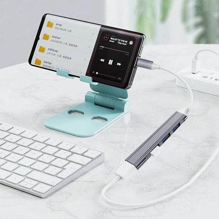 Compact 4-in-1 USB-C Docking Station for Multiple Device Connections shown connected to a phone, keyboard and external drive on a home office desk