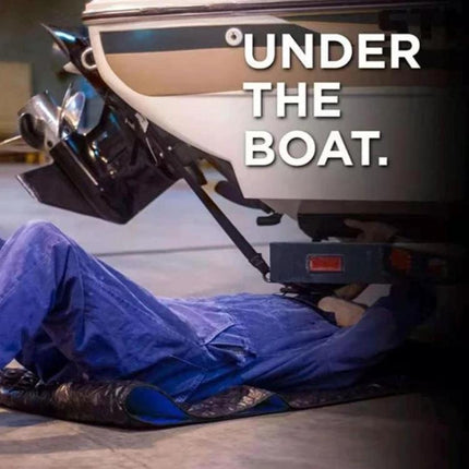 A foldable pad for quick vehicle fixes during travel shown under a boat protecting the person working