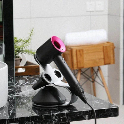 Punch Free Standing Hair Dryer Stand For Dyson Silver on marble salon counter holding a black and pink Dyson-style dryer