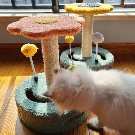 Turntable Cat Scratching Toy for Everyday Home Play - pastel double-level scratching post with pom-pom toys and cat inspecting it in sunlight