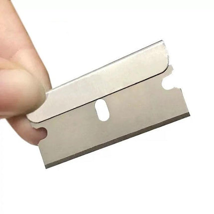 Hand holding a single blade from a 100-pack Stainless Steel Blades for Mobile Screen and Car Film, 100 Pack used for cutting and scraping tasks