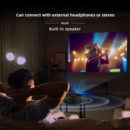 Compact Portable LED Mini Projector for Home Entertainment and Learning showing man watching a concert projected on a wall with built-in speaker and headphones connection