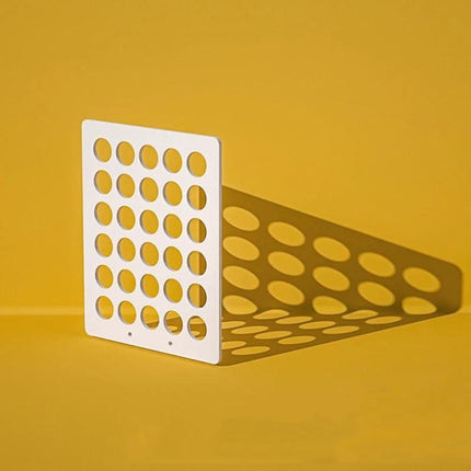 Light Shadow Board for Still Life and Portrait Photography - white perforated board casting patterned shadows on yellow background, waterproof studio prop