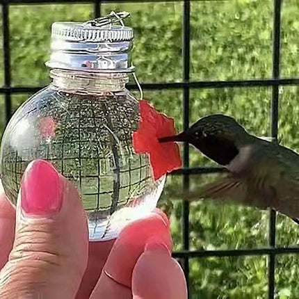 Outdoor Hanging Feeder for Hummingbirds in Your Backyard - close-up of hummingbird feeding from small clear hanging feeder held by hand