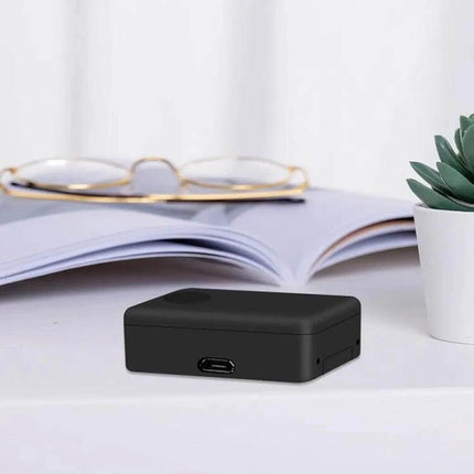 Portable Voice-Activated Anti-Theft Locator for Security Use compact black GSM voice-activated device on desk near glasses and plant