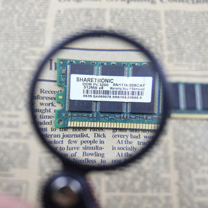 8X Mini Leather Folding Magnifier for Reading and Repair showing magnified RAM module and newspaper text
