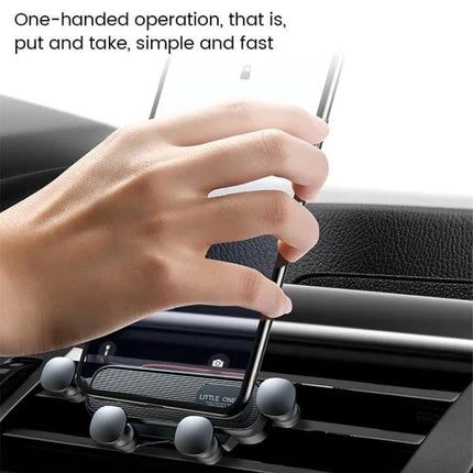 Black Vehicle Air Outlet Gravity Phone Holder For Cars shown mounted on car air vent with hand placing smartphone for one-handed use