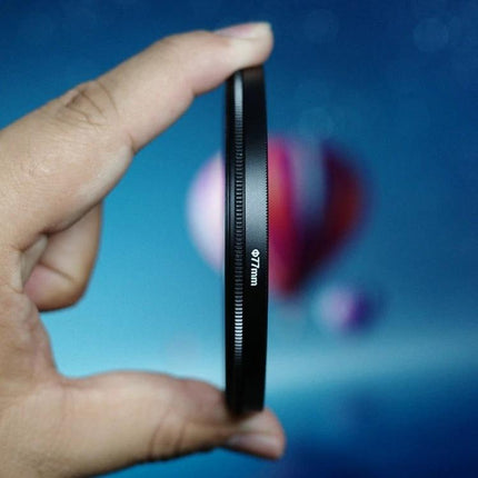 Double Half Moon Foreground Blur Filter for Photography held between fingers showing thin optical glass and blurred colorful background