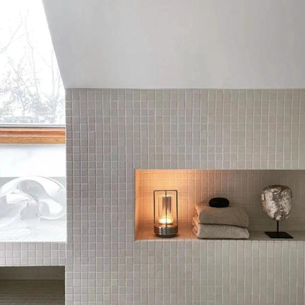 A Lamp That Lights Up Your Home and Camping Nights Easily - portable lantern styled lamp glowing on tiled shelf beside towels and decor