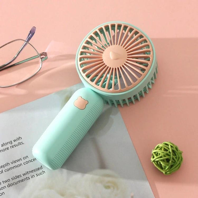 Compact Portable Handheld Electric Fan for Everyday Cooling mint green handheld fan on desk with glasses and decor