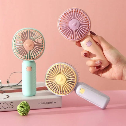 Compact Portable Handheld Electric Fan for Everyday Cooling in pastel colors held and displayed on a desk