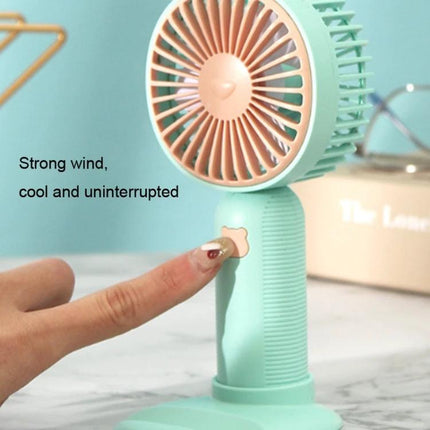 Handheld Portable Fan for Everyday Cooling and Travel Use - Compact mint handheld fan with stand and phone holder, shown being turned on