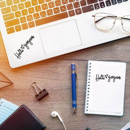 Hello Gorgeous Inverted Rear Mirror Glass Car Sticker shown on laptop and notebook next to pen and glasses, black PVC decal for rear mirror personalization
