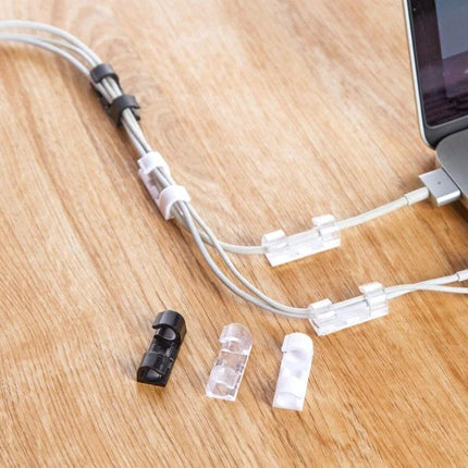 Set of 20 Adhesive Cable Clips for Home Wire Organization showing clear and black clips securing laptop and charger cables on a wooden desk