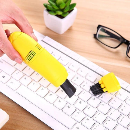 Portable USB-Powered Keyboard Cleaning Brush for Dust Removal used to clean white computer keyboard with yellow handheld vacuum and brush