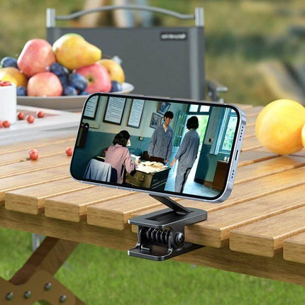 Car Magnetic Phone Holder Clip Stand For Hands-Free Travel shown clipped to a picnic table holding a smartphone for media viewing