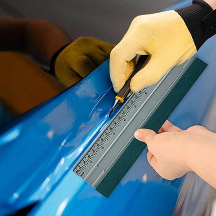Auto Film and Wallpaper Scraper Tool with Graduated Scale held on blue car film with felt edge and ruler for precise cutting