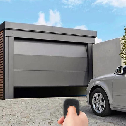 Simple Garage Door Remote Control for Marantec Digital Systems held in hand pointing at closed modern garage door near parked car