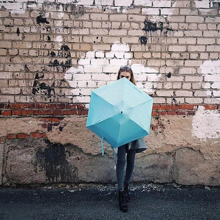 Compact Women's Folding Umbrella for Rain and Sun Protection - compact teal umbrella held by woman for commuting and sun/rain coverage