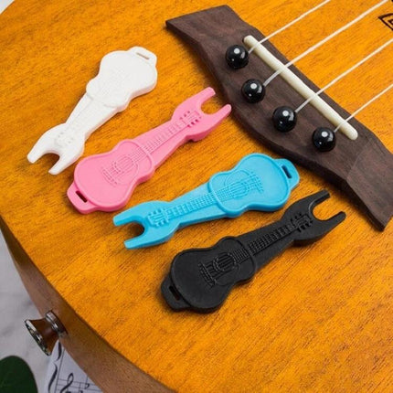 Guitar String Tool for Easy Home Practice Changes — colorful guitar-shaped string changing tools beside a ukulele bridge